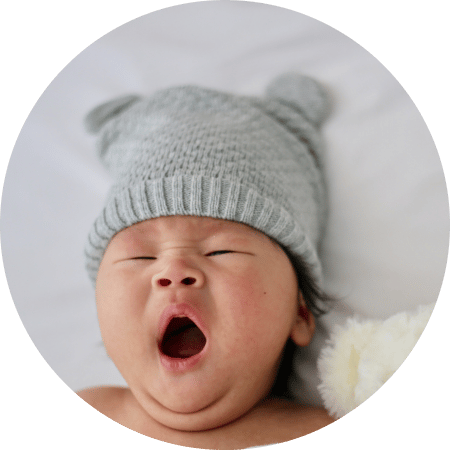 Baby with cap on head yawning