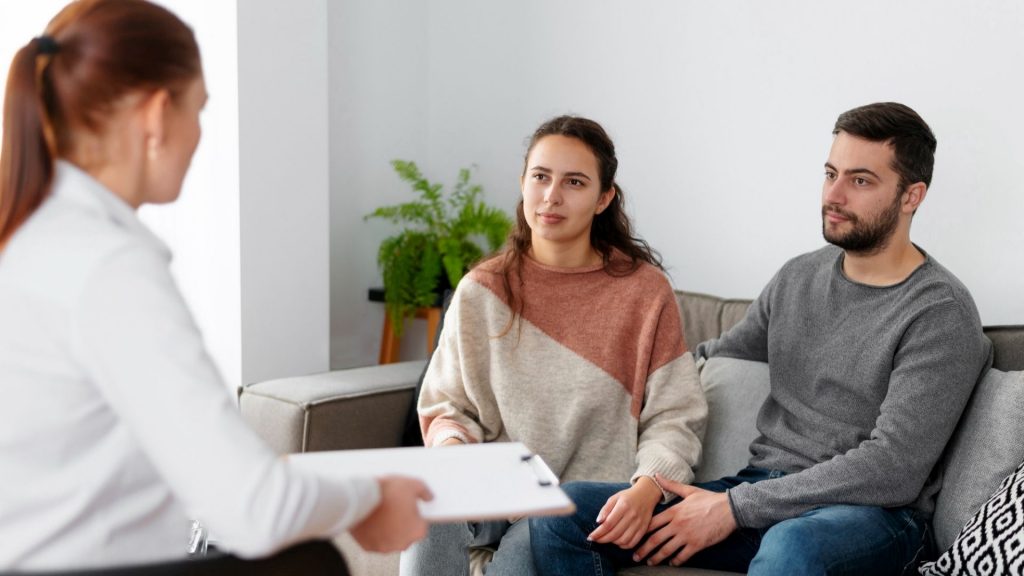 Genetic counselor discussing compatibility test results with two intended parents during a consultation
